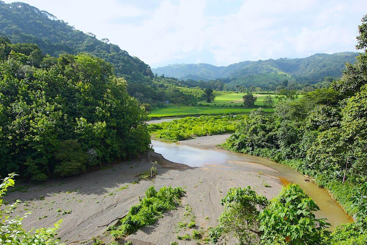 The Tulín River winding between green hills in the Jaco countryside