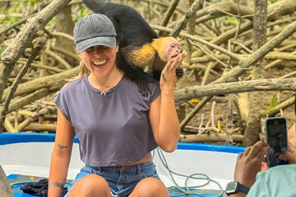 first monkey boards boat and onto the shoulder of guest