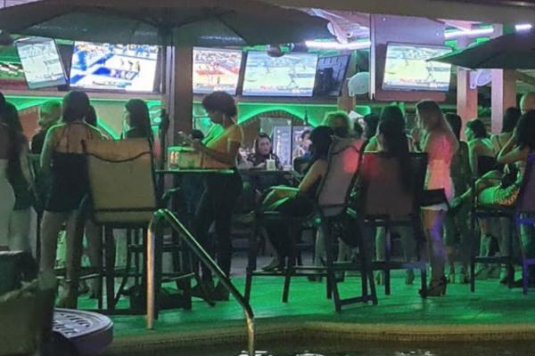 TV wall and bar area with women at Hotel Cocal during nighttime
