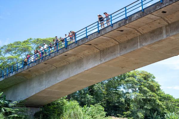 view of Tarcoles Bridge from river with people looking down at crocodile tour boat