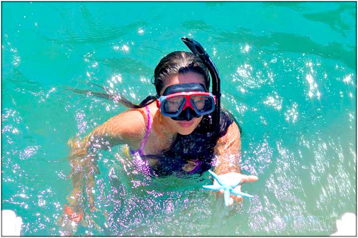 Pretty girl with snorkel gear and blue starfsh on her hand