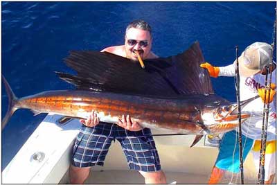Jaco VIP guest with sailfish on lap and smoking a cigar