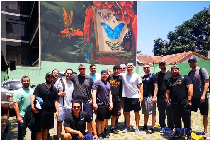 Group and concierge in front of giant macaw mural on side of Pacific Palms