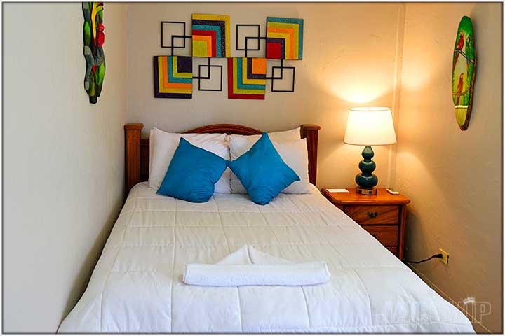 Queen bed with blue pillows and colorful artwork
