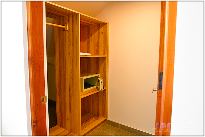 large closet with wood shelves and safebox mounted to wall