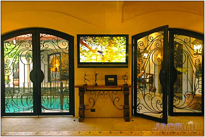 TV between rod iron gate style doors covered with glass