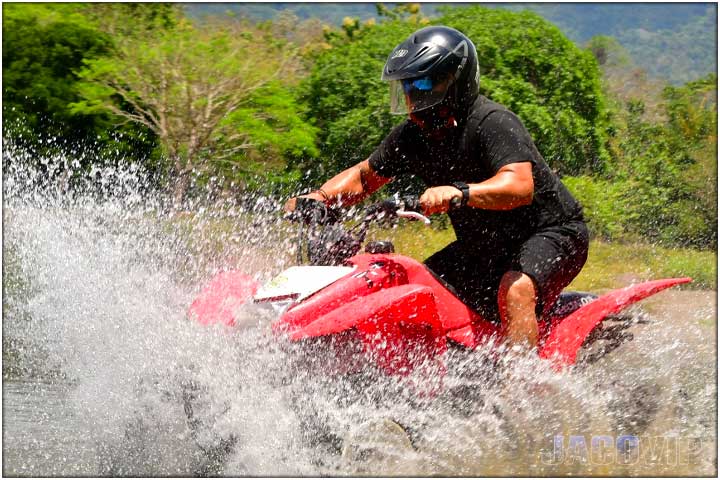 Guy with black clothes crossing river on ATV