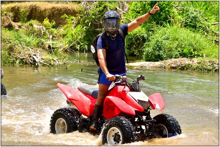 Guy standing up on ATV in river