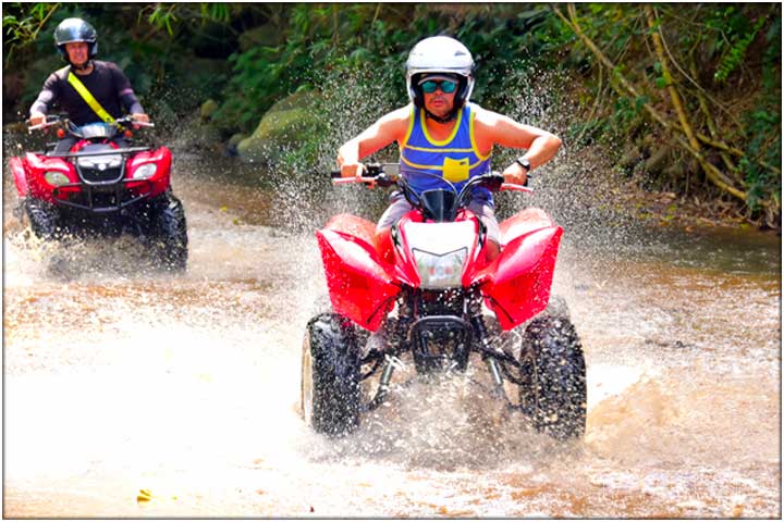 Guys driving ATV across river in Costa Rica