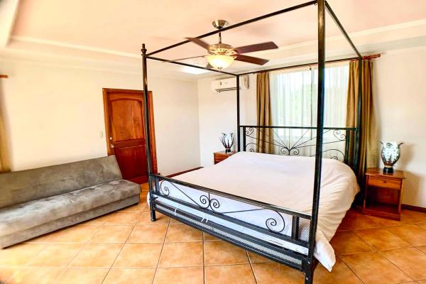 1 King Size Bed Bedroom 1 at Casa Cuatro Jaco with black metal four-poster king bed