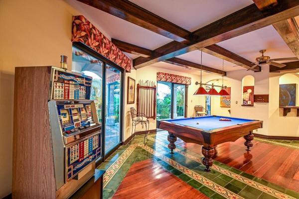 View of the game room with pool table and a slot machine at Casa Patron