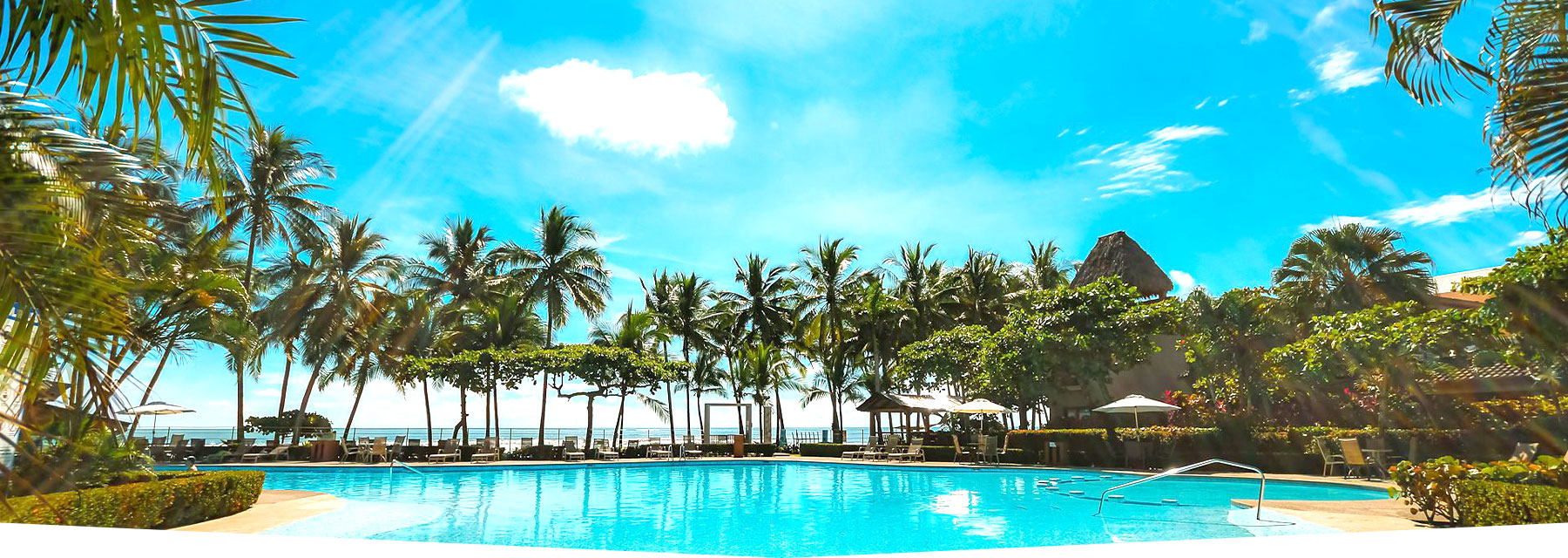 Tropical pool area at Hermosa Palms with palm trees and ocean views in Playa Hermosa, Costa Rica