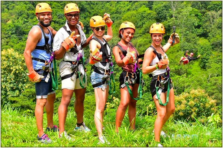 Group posing with guy on zipline in the background