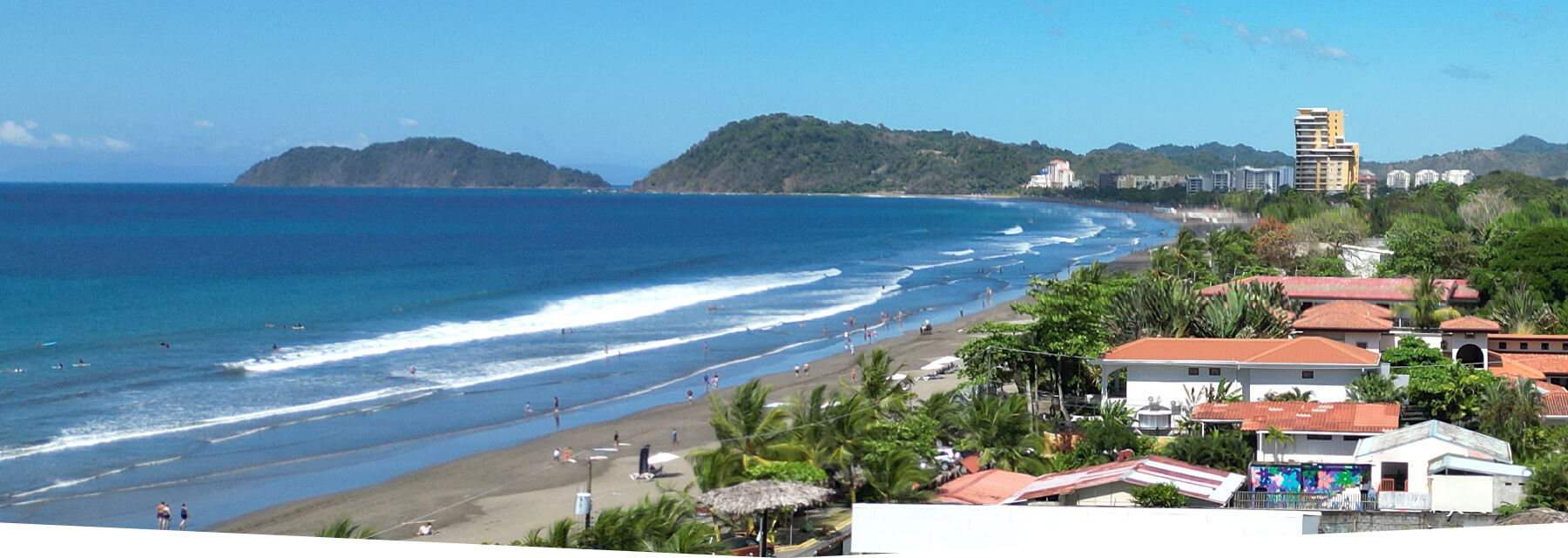 Vibrant daytime drone panorama of Jaco Beach with people and surfers