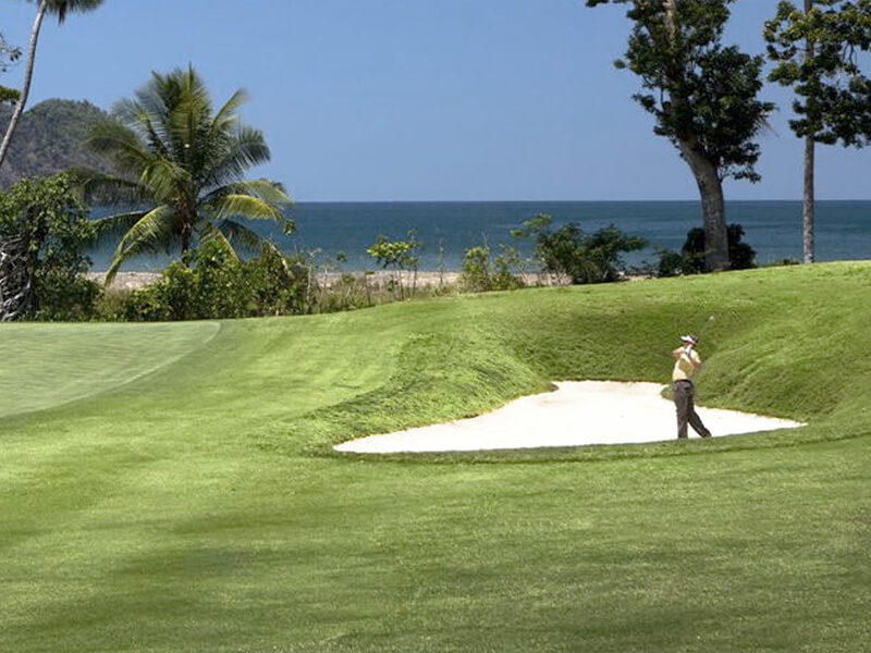 Golfer at La Iguana golf course Los Sueños with Pacific Ocean and beach visible behind