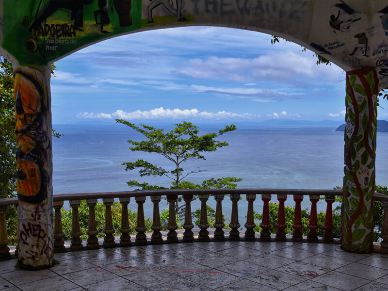 Graffiti covered arch at Miro Mountain ruins framing Pacific Ocean view Jaco Costa Rica
