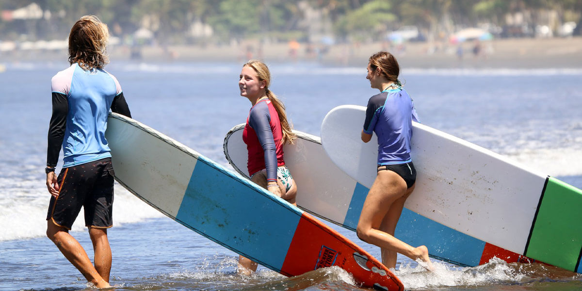 Group carrying surfboards into the ocean for surf lessons at Jaco Beach Costa Rica