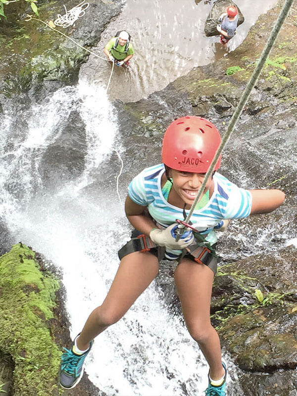 Woman rappelling down a waterfall on canyoning tour near Jaco Beach Costa Rica