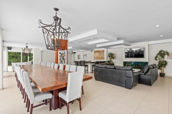 Long wooden dining table with white chairs flanking the leather living room sofas in this expansive open plan layout