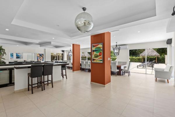 Kitchen bar with high top stools and globe pendant light beside the orange accent column at this Jaco Beach villa retreat