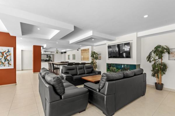 Comfortable living room with leather sectional sofas a wall mounted television and tropical artwork for group gatherings