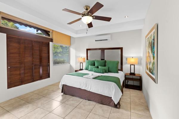 King bed in bedroom two with twin nightstand lamps green accent runner and a wide window for natural light