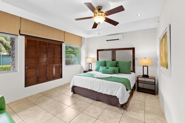 Airy king bedroom 3 with bedside lamps natural decor and en-suite at this welcoming family vacation home near Jaco
