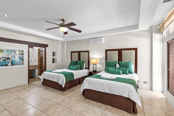 Two queen bedroom 5 with tropical decor wood furnishings and en-suite bathroom at this big group villa near Jaco area