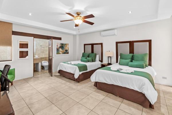 Two queen bedroom 7 with tropical wall art bedside lamps and ceiling fan at this Jaco Beach friendly resort villa home