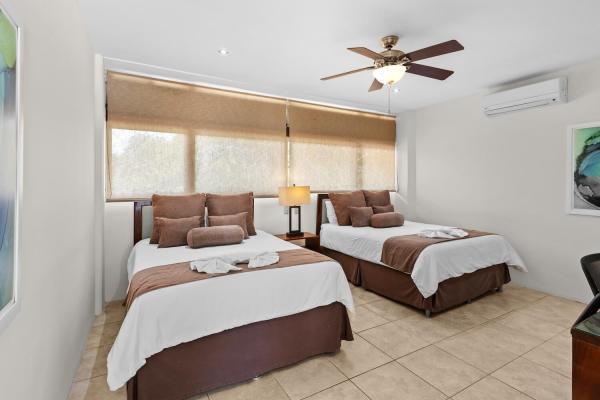 Bright two queen bedroom 9 with bold color accent pillows tropical decor and ceiling fan at this private resort villa