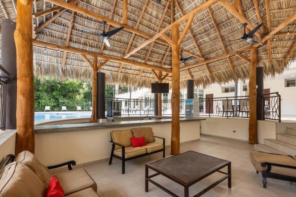 Another angle of the palapa lounge area showing sofas red pillows coffee table and the open thatched ceiling above