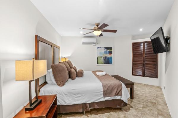 King bedroom 11 with carved headboard tropical art and ceiling fan at Rancho de Sueños private estate near Jaco