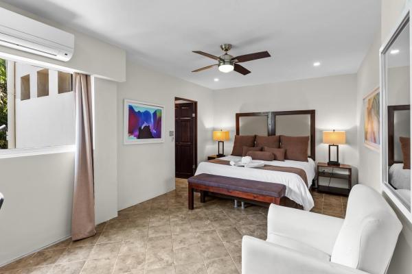 King bedroom 12 with brown linens accent armchair framed art bedside lamps and AC at this large family vacation home