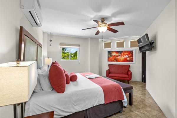 King bedroom 13 with tropical pillows wood furniture and en-suite door at this large family vacation home near Jaco