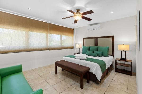 King bedroom 16 with cool tile floors wood headboard ceiling fan and en-suite door at this welcoming Pacific coast home