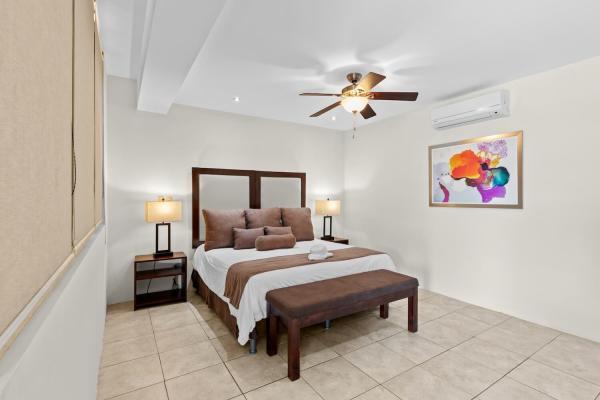 King bedroom 19 with brown pillow accents framed wall art bedside lamps and wood bench at foot at this expansive estate
