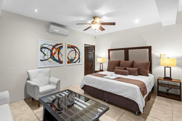 King bedroom 20 with brown pillow accents abstract circular wall art white armchair glass coffee table and ceiling fan