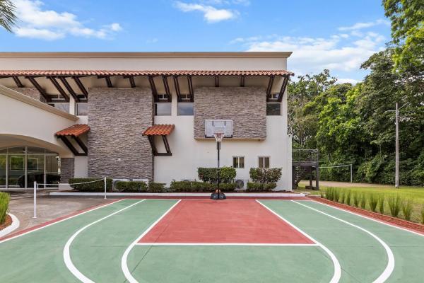 On-site basketball court showing the half court hoop and tile-roof villa exterior with mature tropical landscaping