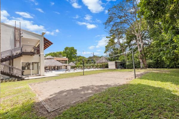 Side yard with grass and sandy ground showing the property building exterior trees and the boundary of the property