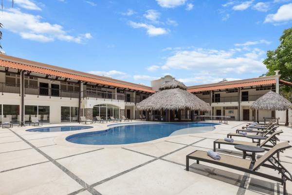 Pool seen from another angle with palapa shade lounge chairs and the two-story building creating an enclosed feel area