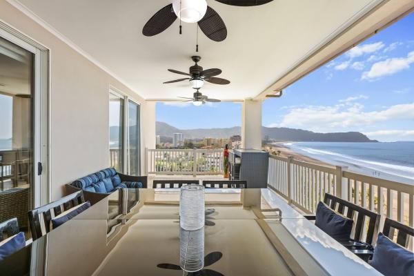 Covered penthouse balcony at The Palms 1002 with outdoor dining table, lounge seating and views of Jaco Beach and the hills