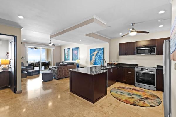 Open-plan kitchen and living area at The Palms 1002 with granite island and ocean view balcony beyond