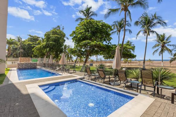 Beachfront swimming pool at The Palms with lounge chairs, palms and Jaco Beach in the background