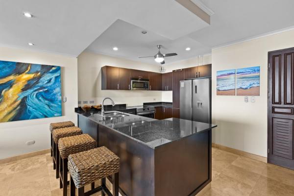 Kitchen at The Palms 1002 with granite breakfast bar, wicker stools and stainless steel appliances