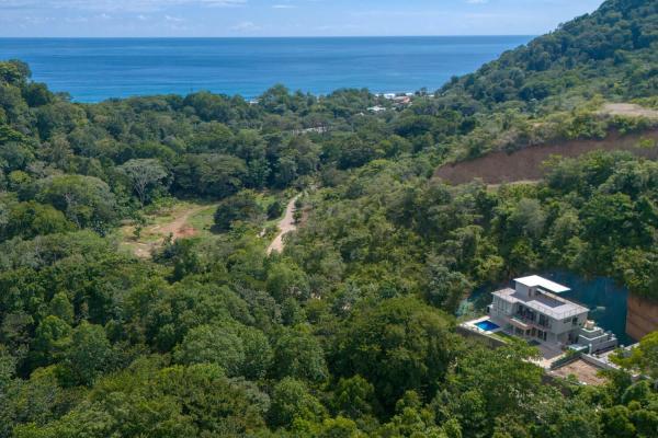 Aerial view of Playa Hermosa jungle hills with Villa Bugambilia and ocean beyond