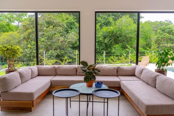 Living room U-shaped sofa facing floor to ceiling jungle windows