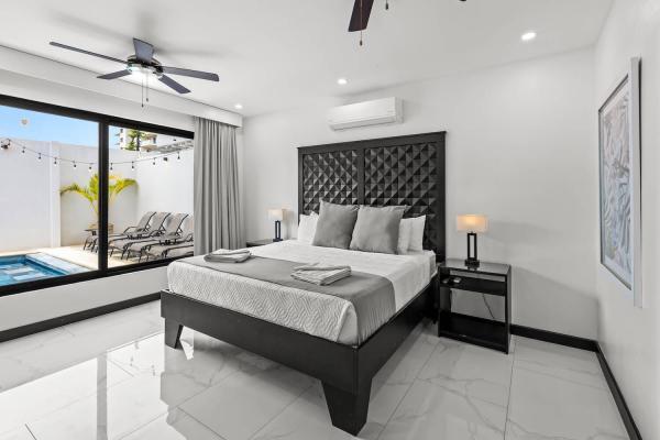 1 King Bed Elegant king bedroom with tufted headboard, ceiling fan, and tropical window views at Villa Norma in Jaco