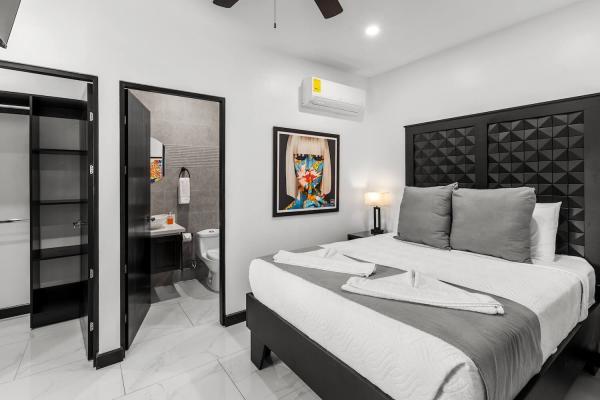 1 King Bed King bedroom with dramatic tufted headboard, bedside reading lamps, and tropical balcony views at Jaco Beach