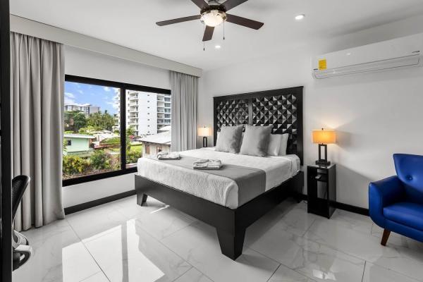 1 King Bed King bedroom suite with plush tufted headboard, warm neutral tones, and tropical palm views at Villa Norma