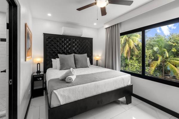 1 King Bed Inviting king bedroom with wide windows overlooking tropical rooftops at this Jaco Beach vacation villa